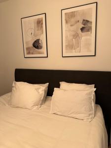 a bed with white sheets and two pictures on the wall at Trump apartment in Stockholm