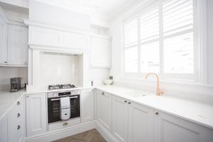 eine weiße Küche mit weißen Schränken und einer Spüle in der Unterkunft Coachman's Cottage- Worthing Beach sleeps 9 in Worthing