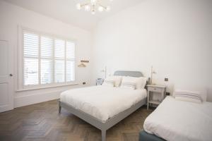 ein weißes Schlafzimmer mit zwei Betten und einem Fenster in der Unterkunft Coachman's Cottage- Worthing Beach sleeps 9 in Worthing
