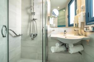 a bathroom with a sink and a shower at Porto Galini Seaside Resort & Spa in Nikiana