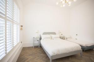 ein weißes Schlafzimmer mit 2 Betten und einem Kronleuchter in der Unterkunft Coachman's Cottage- Worthing Beach sleeps 9 in Worthing