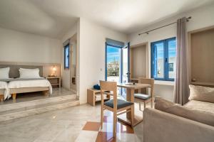 a bedroom with a bed and a table and chairs at Porto Galini Seaside Resort & Spa in Nikiana