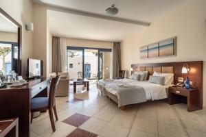 a bedroom with a bed and a desk with a computer at Porto Galini Seaside Resort & Spa in Nikiana