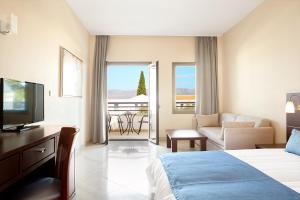 a hotel room with a bed and a couch and a television at Porto Galini Seaside Resort & Spa in Nikiana