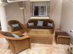 sala de estar con sofá y sillas de mimbre en Villa Bolet, en Chiclana de la Frontera