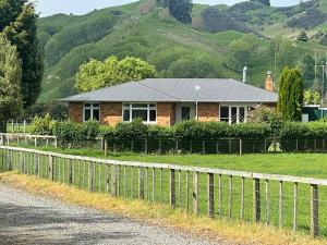 a house with a fence in front of a mountain at River Farm Retreat in Mangaweka