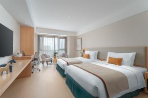 pokój hotelowy z dwoma łóżkami i telewizorem w obiekcie Somerset Fengdong Xi'an w mieście Xianyang