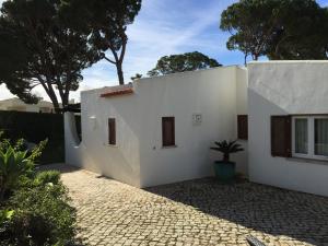 une maison blanche avec une plante en pot devant elle dans l'établissement Vilamoura Villa Alegria, à Vilamoura