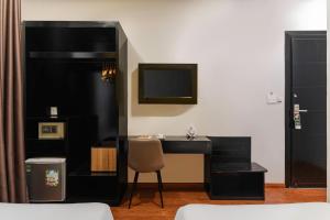 a black desk with a chair and a television in a room at Nature Hotel - Luong The Vinh in Da Lat