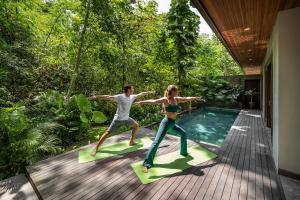 a man and a woman doing yoga by a swimming pool at Suweta Villa Ubud in Ubud