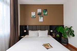 a bedroom with a large white bed and a plant at Nature Hotel - Luong The Vinh in Da Lat +92 photos