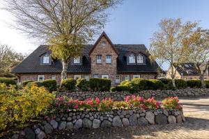 a house with a stone retaining wall and flowers at Sonnenfreude in Westerland