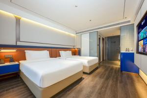 西安市にあるMehood Hotel Xi'an Tumen Railway Stationのベッド2台と薄型テレビ付きのベッドルーム