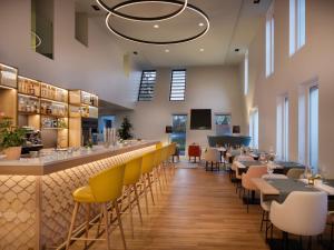a restaurant with a bar with yellow chairs and tables at Hilton Garden Inn Innsbruck Tivoli in Innsbruck