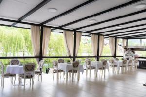 a room with white tables and chairs and windows at Complex Pescăresc Gura Repezii Borșa in Borşa +42 photos