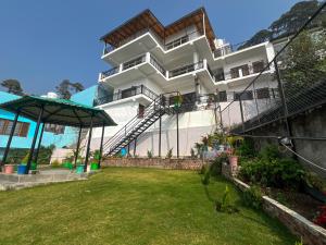 a white building with a lawn in front of it at Manika Homestay in Bhīm Tāl