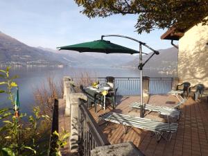 ヴァレンナにあるExclusive Villa Crotto Lake Viewのデッキ(テーブル、椅子、パラソル付)