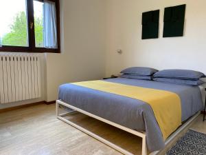 a bedroom with a bed with a yellow and blue blanket at Holiday home Punta D'Oro with garden, parking place and lake access at 300 m in Iseo