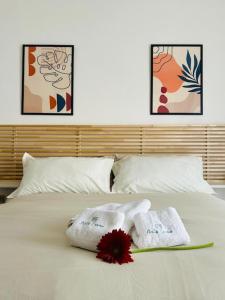 a bed with two towels and a flower on it at Bella Canosa casa vacanza con 3 camere da letto e posto auto custodito in Canosa di Puglia