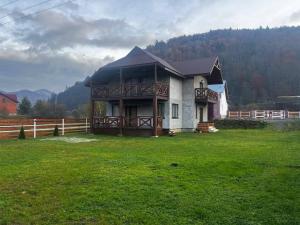 a large house in a field with a fence at Садиба Магнолія in Tukhlya