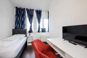 a bedroom with a bed and a chair and a tv at Komfortable 2-Zimmer-Ferienwohnung mit separatem Eingang und Highspeed WLAN in Paderborn