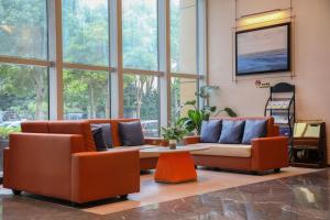 a living room with orange chairs and a couch at Mehood Hotel Zhoushan Putuo Kaihong Plaza in Zhoushan