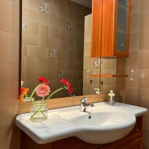 a bathroom sink with a vase with flowers in it at Bella Canosa casa vacanza con 3 camere da letto e posto auto custodito in Canosa di Puglia