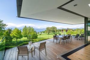 an open patio with tables and chairs on a deck at Maison du Golf in Publier