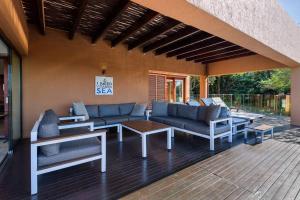 un patio avec des canapés et une table sur une terrasse dans l'établissement San Lameer Villa 1604 - 4 Bedroom Premier - 8 pax - San Lameer Rental Agency, à Southbroom