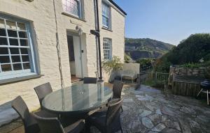 un tavolo in vetro e sedie di fronte a un edificio di Cove Cottage a Portloe