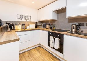 a kitchen with white cabinets and wooden floors at Modern 2 bedroom Flat in Montrose in Montrose