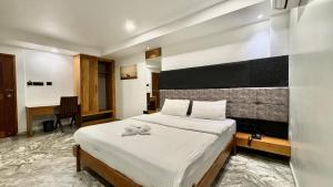 a bedroom with a large white bed and a desk at Luxe Inn in Kannur