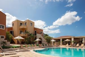 a resort with a swimming pool with chairs and umbrellas at Dia Apartments in Hersonissos