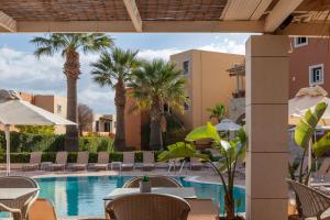 a pool at a resort with chairs and palm trees at Dia Apartments in Hersonissos
