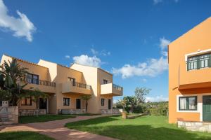 a row of houses with a green lawn in front at Dia Apartments in Hersonissos