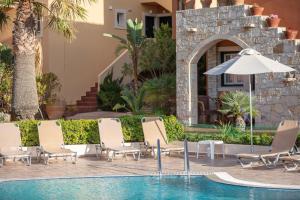 a group of chairs and an umbrella next to a swimming pool at Dia Apartments in Hersonissos