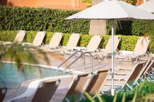 a row of chairs and an umbrella next to a pool at Dia Apartments in Hersonissos