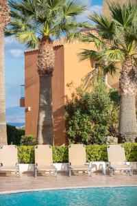 a group of chairs and palm trees next to a pool at Dia Apartments in Hersonissos
