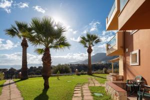 a yard with palm trees and a building at Dia Apartments in Hersonissos