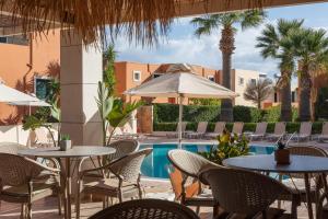 a patio with tables and chairs and a swimming pool at Dia Apartments in Hersonissos
