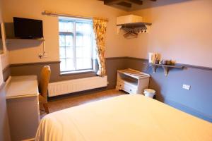 a bedroom with a bed and a window and a desk at Ye Old Boote Inn in Whittington