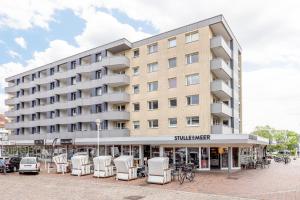 ein großes Gebäude mit weißen Stühlen davor in der Unterkunft Appartement Kleeblatt in Westerland