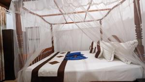a bedroom with a canopy bed with a blue shirt on it at Hirikatiya Edge in Dickwella