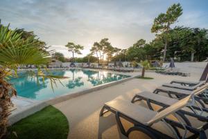 a swimming pool with lounge chairs and a table at Hôtel Les Grenettes in Sainte-Marie-de-Ré