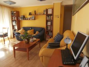 ein Wohnzimmer mit einer Couch und einem Schreibtisch mit einem Computer in der Unterkunft Hostal El Volante in Estella