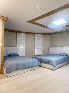江南新论岘地铁站单间公寓可住四人4b في سول: سريرين في غرفة نوم مع ملاءات زرقاء