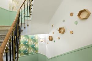 a staircase with a white wall with a green leaf wallpaper at Hotel Florence Nice in Nice