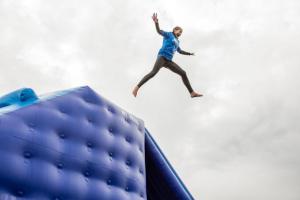 a man is jumping off of a blue mattress at West Chalet At Tapnell Farm in Yarmouth