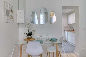 cocina con mesa de cristal y sillas blancas en Léandre studio entièrement rénové avec extérieur, en Rouen