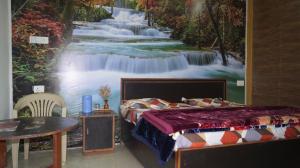 a bedroom with a painting of a waterfall at The ORION Homestay in Mukteswar